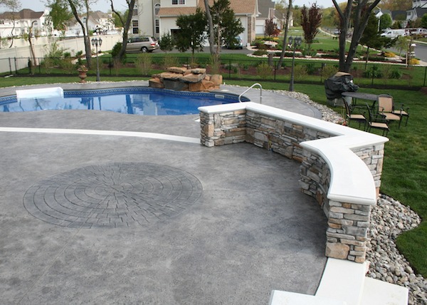 stamped concrete, cultured stone, retaining wall, white bullnose capping, natural stone pool waterfall